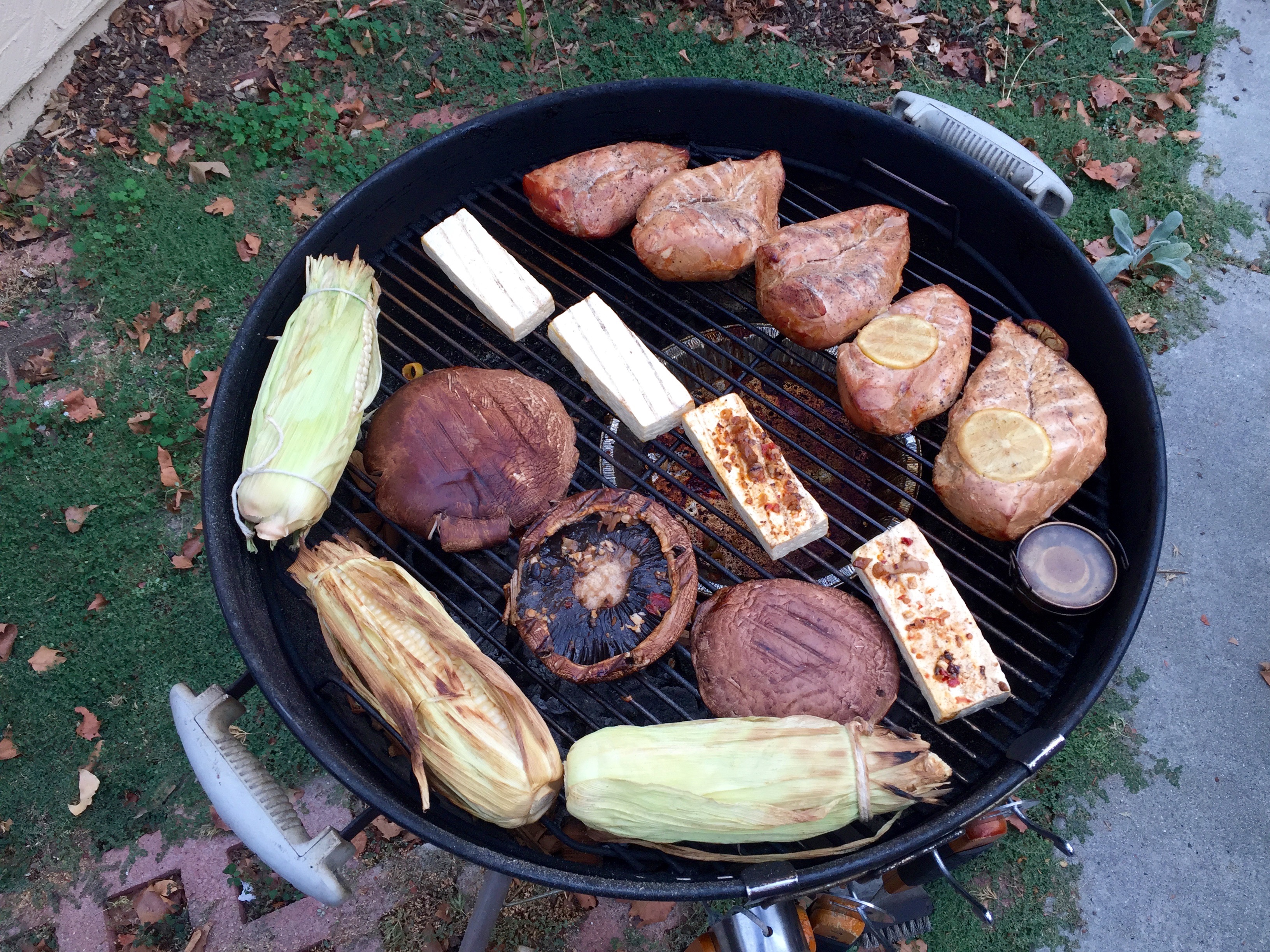 Smoked chicken, corn, mushrooms, and tofu on a kettle grill.